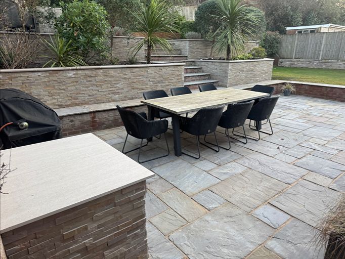 Natural stone patio with outdoor dining area and raised garden beds